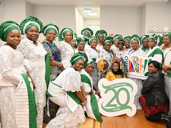 Nigerian nurses in traditional dress holding sign for 20 years of international section